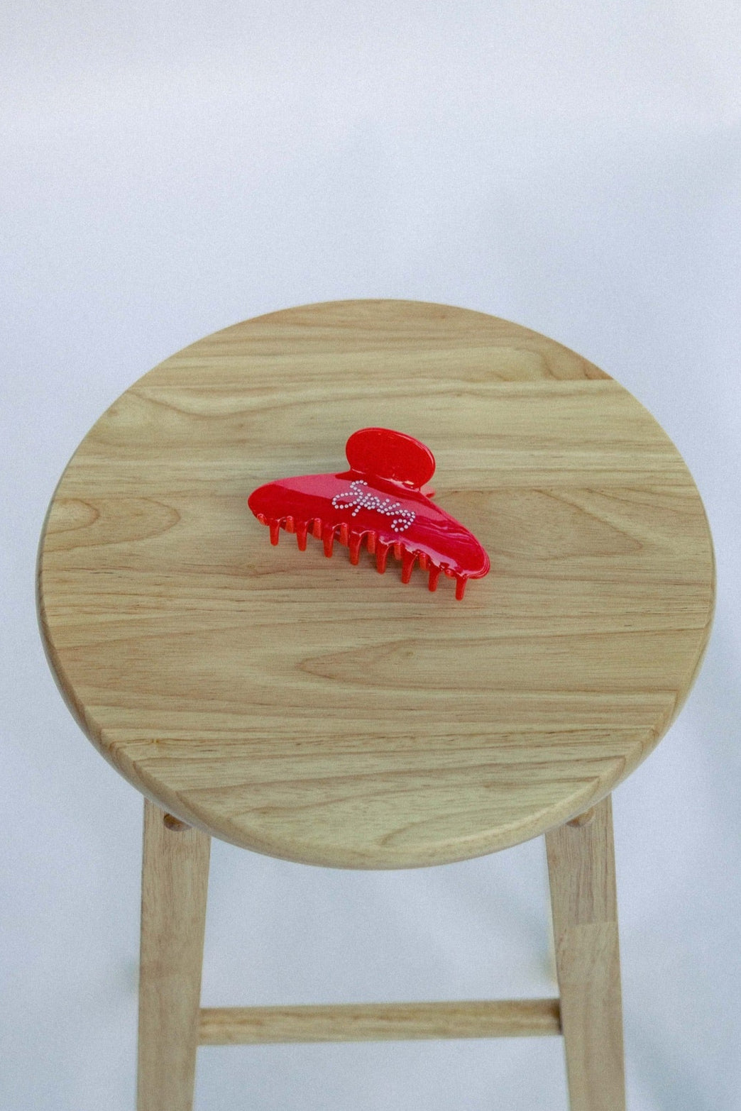 Red hair clip on a wooden stool against a white background